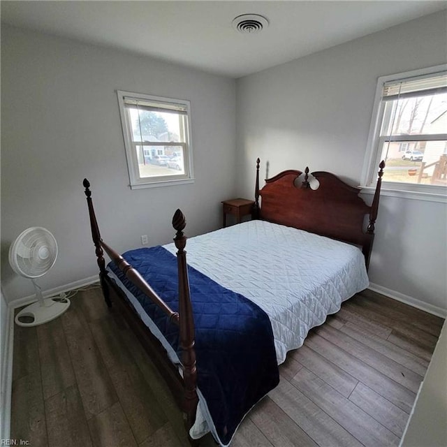 bedroom featuring multiple windows, wood finished floors, visible vents, and baseboards