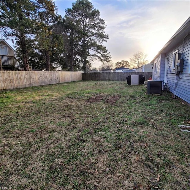 yard at dusk with fence and central AC