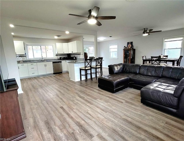 living area with light wood-type flooring, plenty of natural light, and a ceiling fan