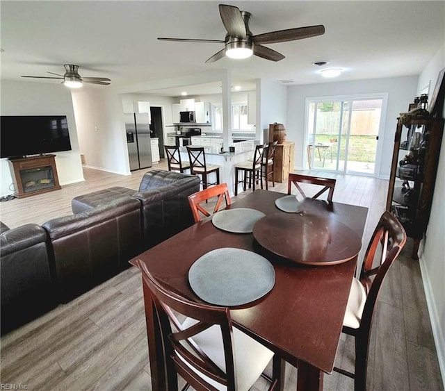 dining room featuring light wood-style floors, baseboards, and ceiling fan