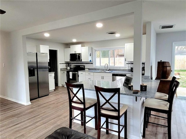 kitchen featuring a breakfast bar area, visible vents, a sink, appliances with stainless steel finishes, and tasteful backsplash