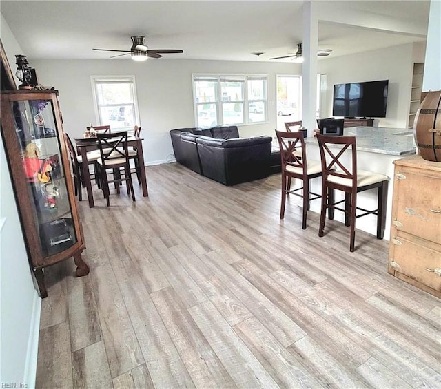 living room with light wood-style flooring, baseboards, and ceiling fan