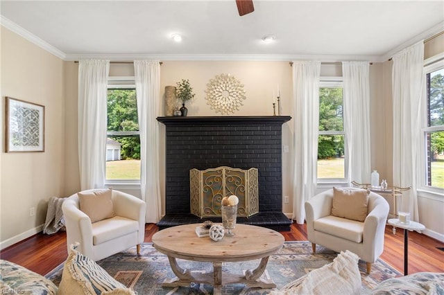 living area with healthy amount of natural light, a brick fireplace, baseboards, and ornamental molding