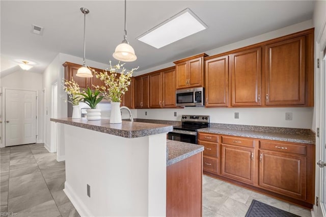 kitchen featuring brown cabinetry, visible vents, a kitchen island with sink, stainless steel appliances, and hanging light fixtures