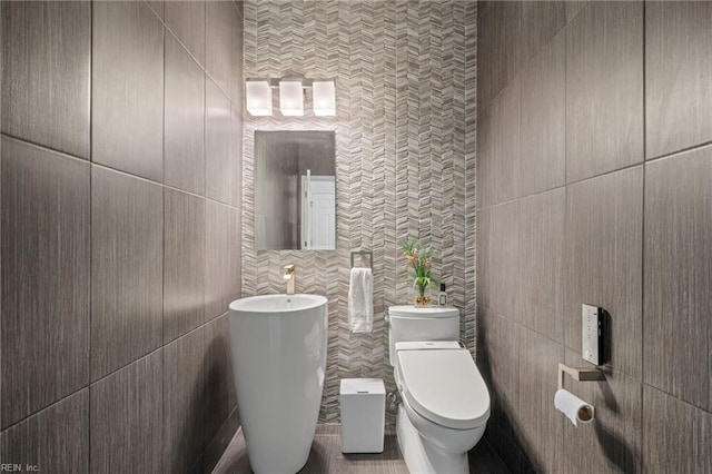 bathroom with toilet and tile walls