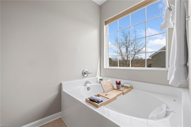 full bathroom with a wealth of natural light, tile patterned flooring, baseboards, and a garden tub