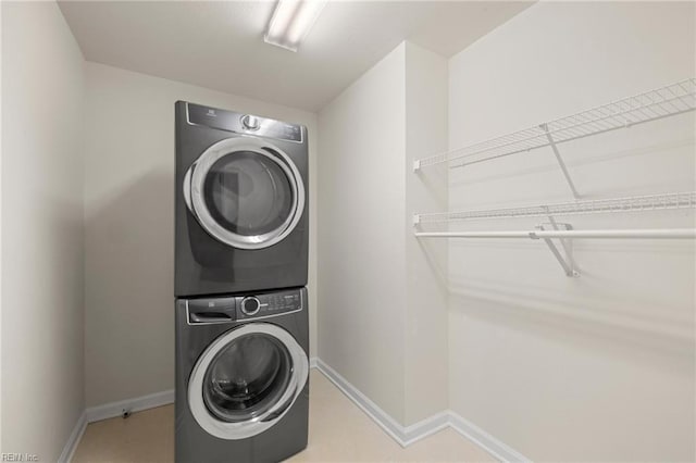 clothes washing area with laundry area, baseboards, and stacked washer and dryer