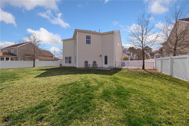 back of house with a fenced backyard and a yard