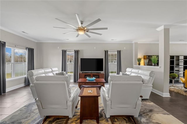 living area with baseboards, crown molding, and ceiling fan