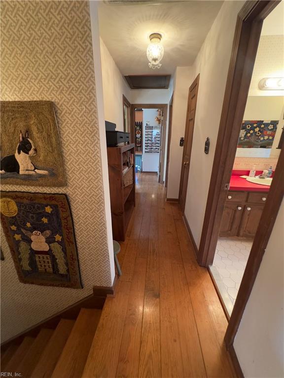 corridor with baseboards, light wood-style flooring, and wallpapered walls