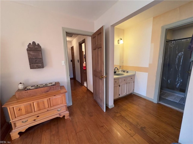 hallway featuring a sink and dark wood-style floors