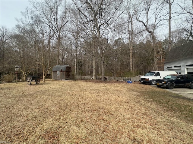 view of yard with concrete driveway, a storage unit, an outdoor structure, and fence