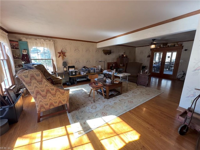 living room with ornamental molding, french doors, wallpapered walls, and wood finished floors