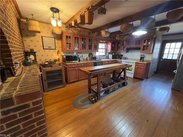 kitchen featuring wallpapered walls, beam ceiling, glass insert cabinets, wood-type flooring, and appliances with stainless steel finishes