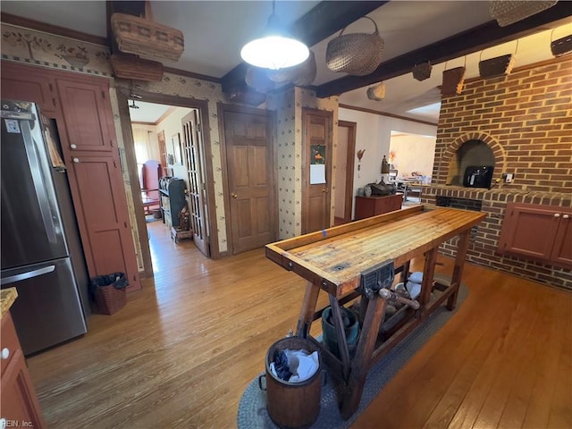 dining space with wallpapered walls, light wood-type flooring, and ornamental molding