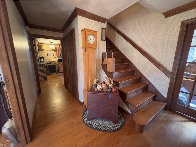 staircase featuring wallpapered walls, baseboards, and wood finished floors