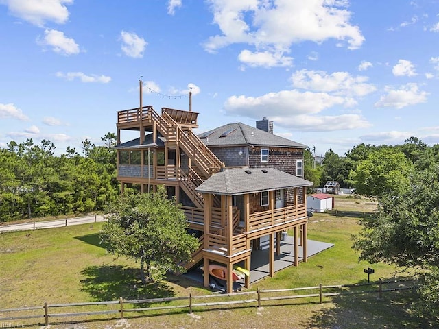 rear view of house with a lawn, fence, stairway, roof with shingles, and a wooden deck