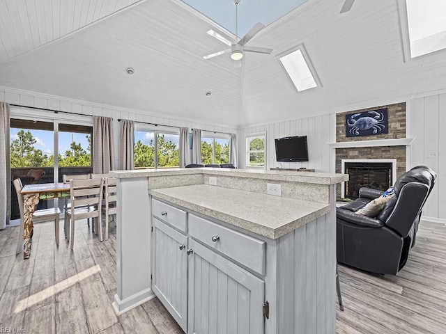 kitchen with a ceiling fan, a kitchen island, light wood-style flooring, plenty of natural light, and light countertops