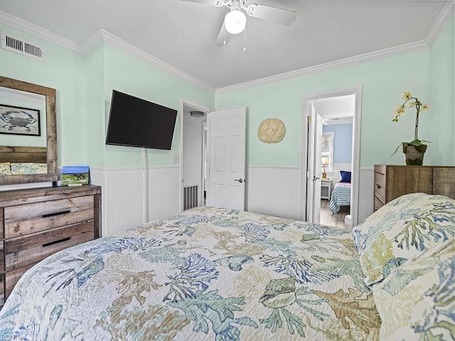 bedroom with visible vents, ceiling fan, wainscoting, and crown molding