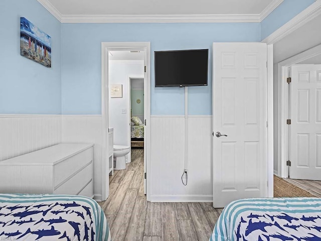 bedroom featuring crown molding, light wood-type flooring, and wainscoting