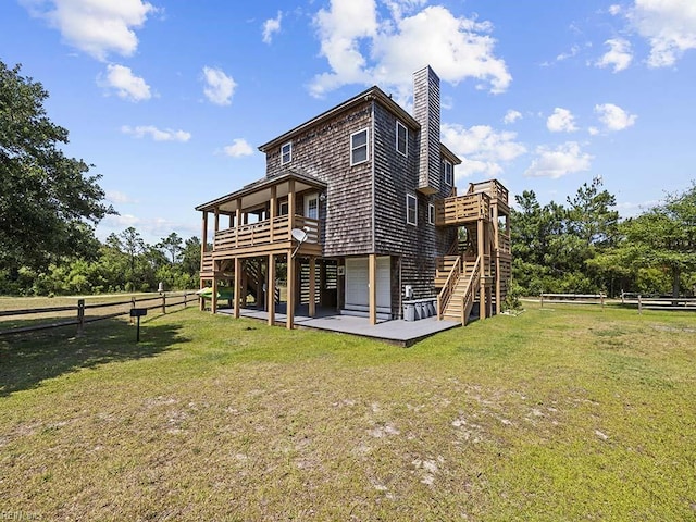 rear view of house featuring a wooden deck, a lawn, stairs, and fence