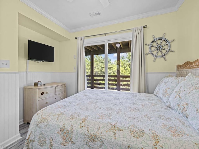 bedroom featuring wood finished floors, visible vents, ornamental molding, access to exterior, and wainscoting