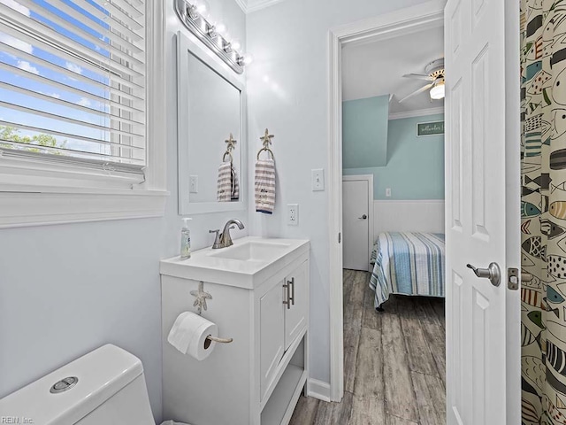 bathroom featuring vanity, wood finished floors, ceiling fan, ornamental molding, and toilet