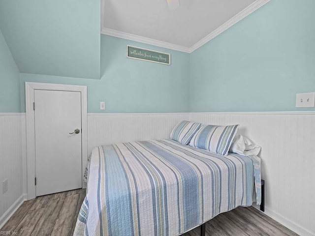 bedroom with wainscoting, crown molding, a ceiling fan, and wood finished floors