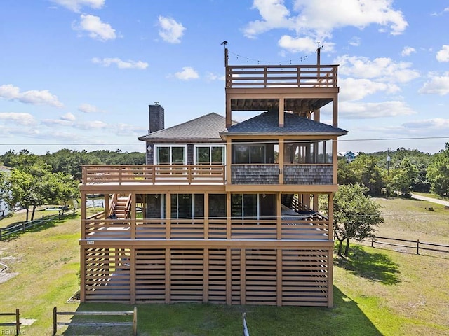 rear view of property featuring a deck, a sunroom, a yard, and fence