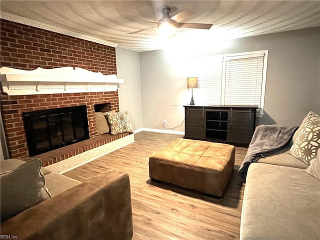 living area featuring wood finished floors, a fireplace, baseboards, and ceiling fan