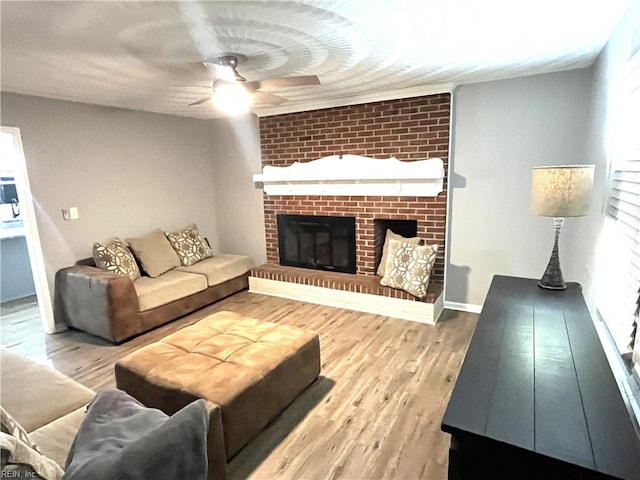 living area with a brick fireplace, wood finished floors, and a ceiling fan