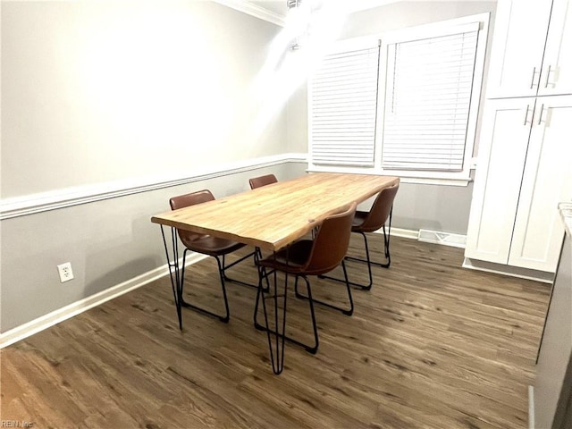 dining room featuring dark wood finished floors, crown molding, and baseboards