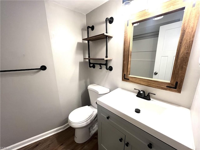 bathroom with baseboards, toilet, wood finished floors, and vanity