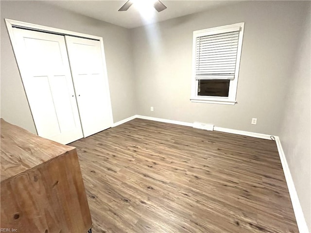 unfurnished bedroom featuring a closet, a ceiling fan, baseboards, and wood finished floors