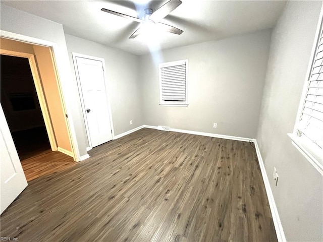 unfurnished bedroom with dark wood finished floors, a closet, a ceiling fan, and baseboards