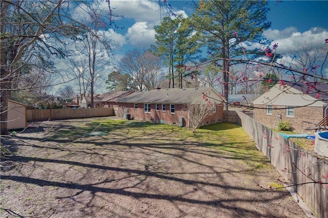 exterior space with brick siding, a lawn, an outdoor structure, and a fenced backyard