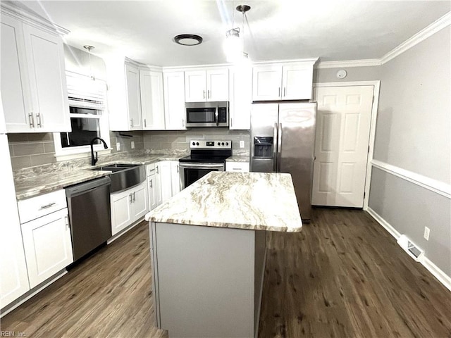 kitchen with decorative backsplash, appliances with stainless steel finishes, a center island, and a sink