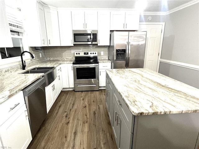 kitchen with gray cabinets, a sink, stainless steel appliances, crown molding, and decorative backsplash