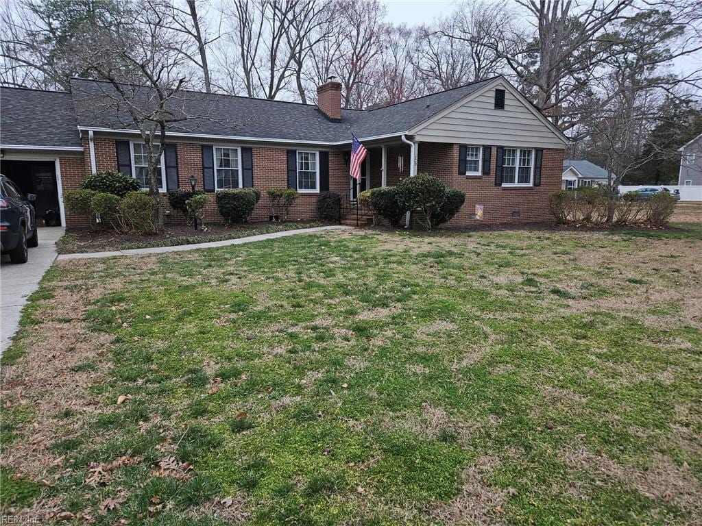 ranch-style house with brick siding, a chimney, a front yard, and a shingled roof