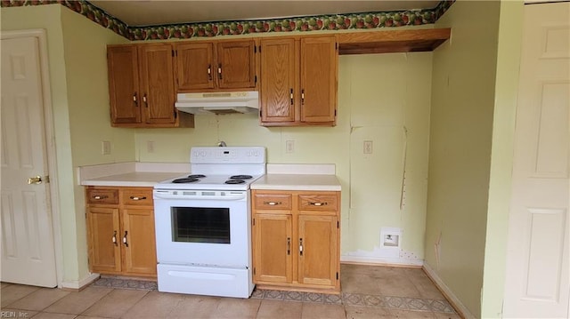 kitchen with baseboards, under cabinet range hood, light countertops, brown cabinets, and white electric range