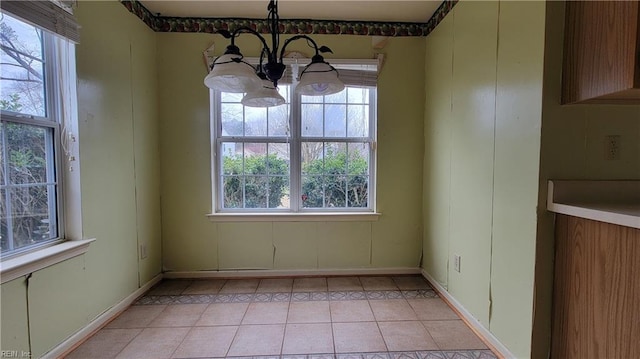 unfurnished dining area with light tile patterned floors, baseboards, and an inviting chandelier