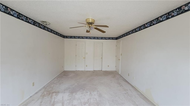 unfurnished room featuring visible vents, a textured ceiling, ceiling fan, and carpet flooring