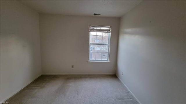 empty room featuring visible vents, light carpet, and baseboards