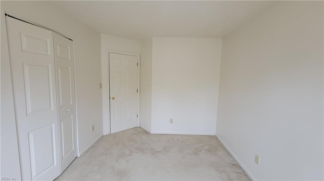 unfurnished bedroom featuring baseboards and light carpet