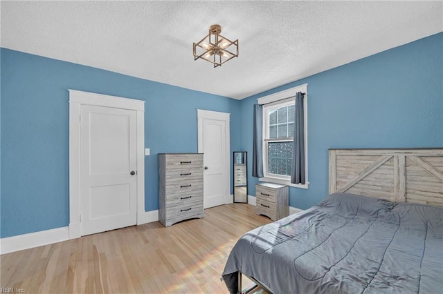 bedroom featuring wood finished floors, baseboards, and a textured ceiling