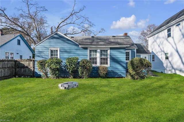 back of property with a yard, fence, and a fire pit