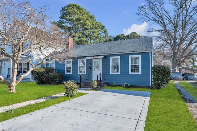 view of front of property featuring driveway, a chimney, a front yard, and a shingled roof