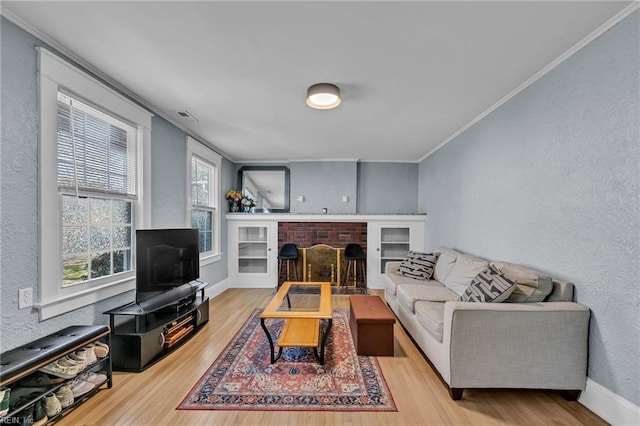 living room featuring crown molding, baseboards, a textured wall, a fireplace, and wood finished floors