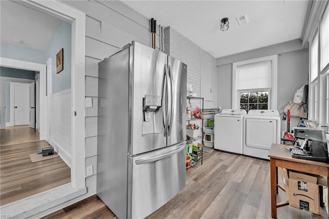 kitchen with visible vents, independent washer and dryer, wood finished floors, and stainless steel fridge with ice dispenser