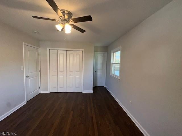 unfurnished bedroom featuring dark wood finished floors, a closet, and baseboards